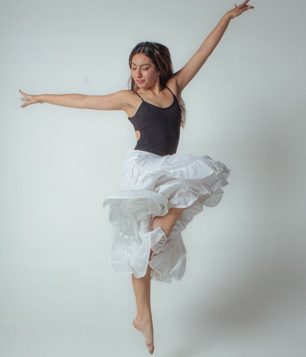 A person in a fluid motion pose inside a minimalist studio.